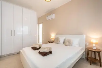 a white bedroom with a large white bed with towels on it at Spiti Apartment Ialysos in Ialyssos