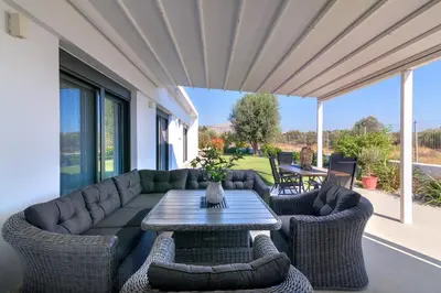 a patio with a couch and chairs and a table at Villa Galini in Haraki