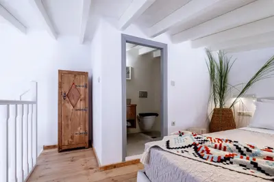 a bedroom with white walls and a bed and a mirror at Mea Casa Halki in Halki