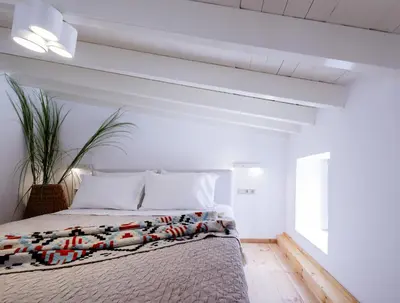 a white bedroom with a bed and a window at Mea Casa Halki in Halki