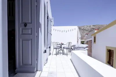 a white balcony with a table and chairs on it at Mea Casa Halki in Halki