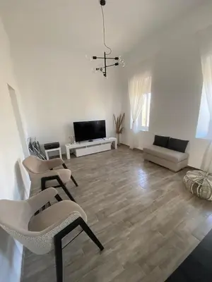 a living room with chairs and a couch and a television at Angelica Residence in Gennadi