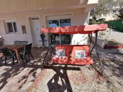 a red umbrella on a patio with a table at Villa Klelia in Afantou