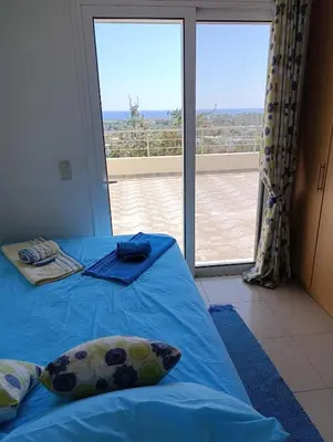 a bedroom with a blue bed and a large window at Villa Klelia in Afantou