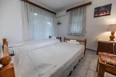 a bedroom with two beds and a desk and a window at Villa Hara Kiotari in Gennadi