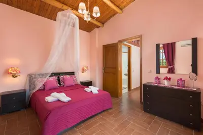 a bedroom with a pink bed and a mirror at Villas Marianna in Kalavárda