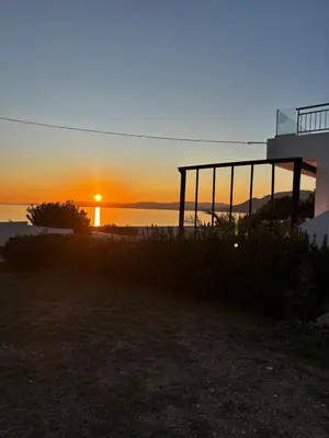a sunset from a house with the sun setting over the water at Amphora Sea View Pefkos in Pefki Rhodes