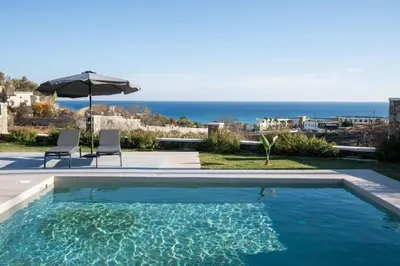 a swimming pool with two chairs and an umbrella at Villa Kiki, Kiotari in Asklipiḯon