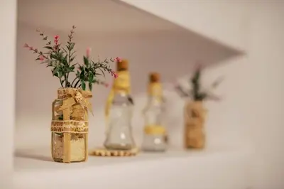 a shelf with bottles and a vase with flowers in it at Nora's ixia summer house in Ialyssos