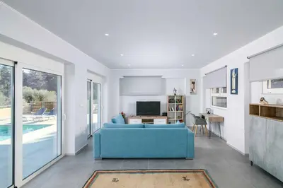 a living room with a blue couch and a tv at Villa Anastazia in Koskinou