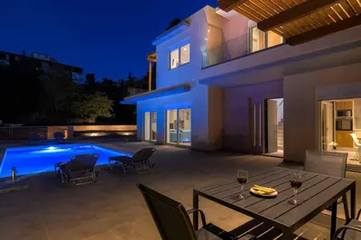a patio with a table and chairs next to a swimming pool at Villa Anastazia in Koskinou