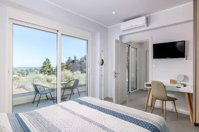 a bedroom with a bed and a desk and a balcony at Villa Anastazia in Koskinou
