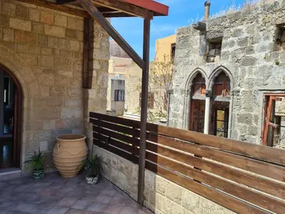 a patio with a wooden fence next to a building at Shades of Wood Old Town in Rhodes Town