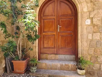 a wooden door on a stone building with potted plants at Shades of Wood Old Town in Rhodes Town