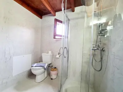 a bathroom with a toilet and a glass shower at Shades of Wood Old Town in Rhodes Town