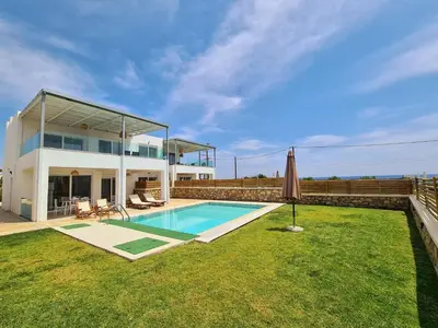 a house with a swimming pool and an umbrella at The 4th Seaview Villas in Kiotari