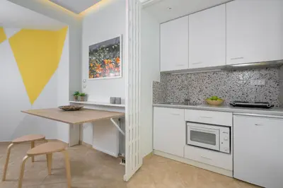 a kitchen with white cabinets and a table and chairs at Rodini Anassa in Rhodes Town