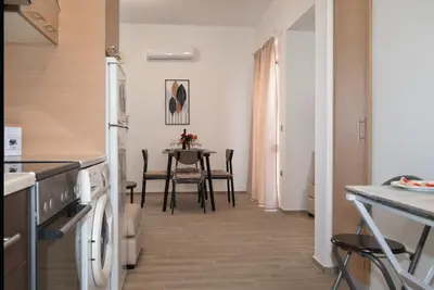 a kitchen with a table and a white refrigerator at Filerimos City Center Apt in Ialysos Rhodes in Ialyssos