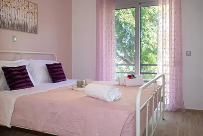 a bedroom with two beds with purple pillows and a window at Filerimos City Center Apt in Ialysos Rhodes in Ialyssos