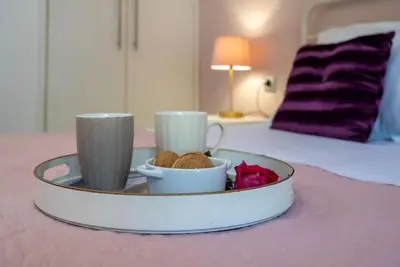 a tray with two cups and cookies on a bed at Filerimos City Center Apt in Ialysos Rhodes in Ialyssos
