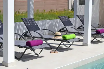 four chairs with colorful cushions next to a pool at Azure Dreams Villa with pool - Haraki beach in Haraki