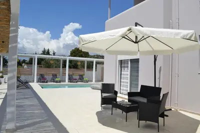 a patio with an umbrella and chairs and a pool at Azure Dreams Villa with pool - Haraki beach in Haraki