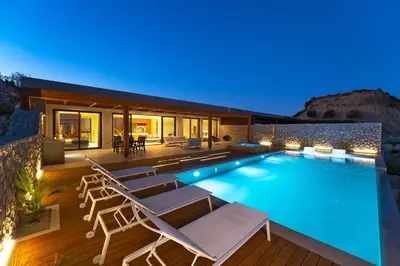 a swimming pool with lounge chairs and a house at Under The Sun on Faliraki Hill in Kalithies