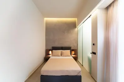 a small bedroom with a bed and a window at Under The Sun on Faliraki Hill in Kalithies