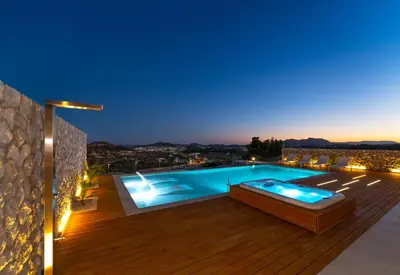 a swimming pool on the deck of a house at night at Under The Sun on Faliraki Hill in Kalithies