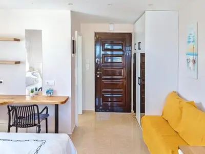 a living room with a yellow couch and a table at 7-Modern city center studio with sea view! in Rhodes Town