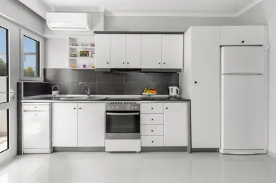 a white kitchen with white cabinets and appliances at 5- Luxury suite for 4 in the most central part of Rhodes! in Rhodes Town