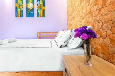 a vase of purple flowers sitting on a table in a bedroom at 5- Luxury suite for 4 in the most central part of Rhodes! in Rhodes Town
