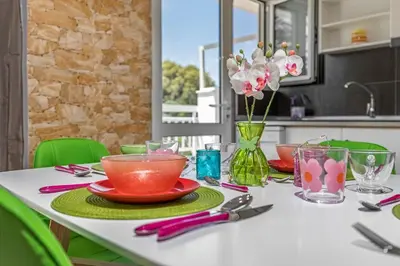 a table with plates and bowls and flowers in a kitchen at 5- Luxury suite for 4 in the most central part of Rhodes! in Rhodes Town