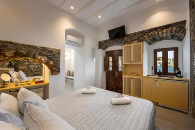 a bedroom with a large bed and a kitchen at Evgenias Sea House in Symi