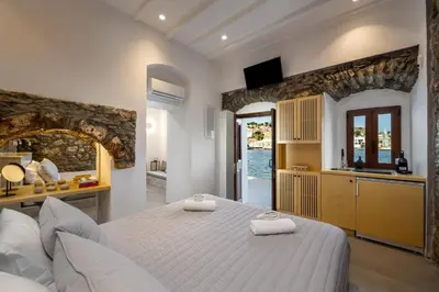a bedroom with a large white bed and a kitchen at Evgenias Sea House in Symi