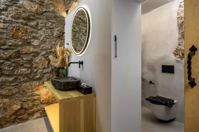 a bathroom with a stone wall and a sink at Evgenias Sea House in Symi