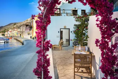 a arch of purple flowers on a building with a street at Evgenias Sea House in Symi