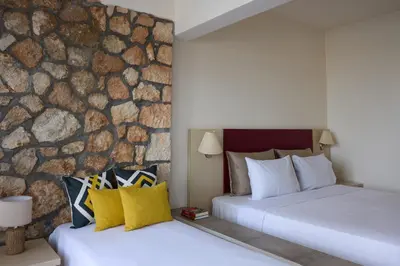 two beds in a hotel room with a stone wall at Blue Bay Beach Resort in Ialyssos