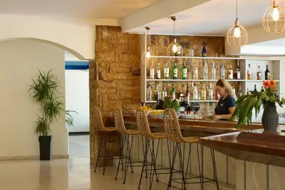 a woman sitting at a bar in a restaurant at Blue Bay Beach Resort in Ialyssos