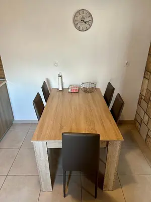 a dining room table with chairs and a clock on the wall at Stone House Retreat in Kalavárda