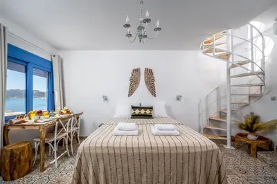 a bedroom with a bed with a table and a staircase at Hermes Seaview House in Archangelos