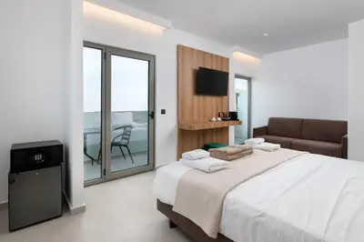 a bedroom with a bed and a couch and a balcony at Rodos White in Rhodes Town