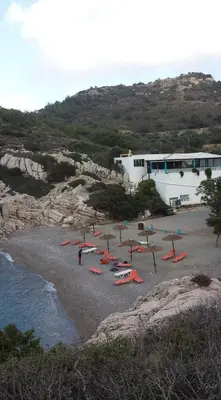 a beach with chairs and umbrellas next to the water at House of Happiness in Kritinía