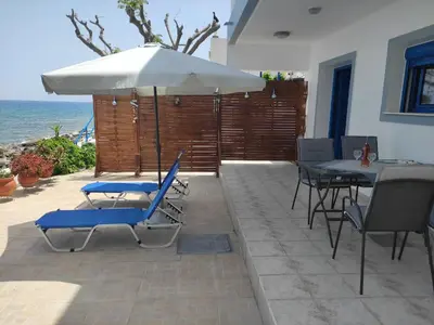 a patio with a table and chairs and an umbrella at Villa Amalia in Vrachonisída touArchangélou