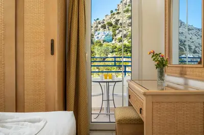a hotel room with a bed and a desk and a window at Evi Studios & Apartments Pefkos in Pefki Rhodes