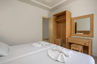 a bedroom with a white bed and a mirror at Evi Studios & Apartments Pefkos in Pefki Rhodes