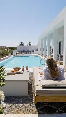 a woman laying on a bed next to a swimming pool at Seashell Villa - Luxury Pool Retreat - 150m Beach in Lachania