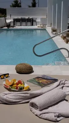 a plate of fruit and a book next to a swimming pool at Seashell Villa - Luxury Pool Retreat - 150m Beach in Lachania
