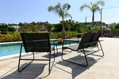 two chairs and a glass table next to a swimming pool at Aetheria Luxury Villa in Kalithies
