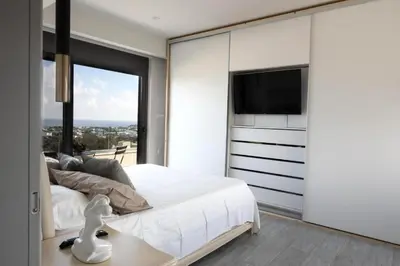 a bedroom with a large white bed and a flat screen tv at Aetheria Luxury Villa in Kalithies